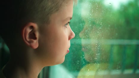 Niño-Mirando-La-Lluvia-A-Través-De-Una-Ventana