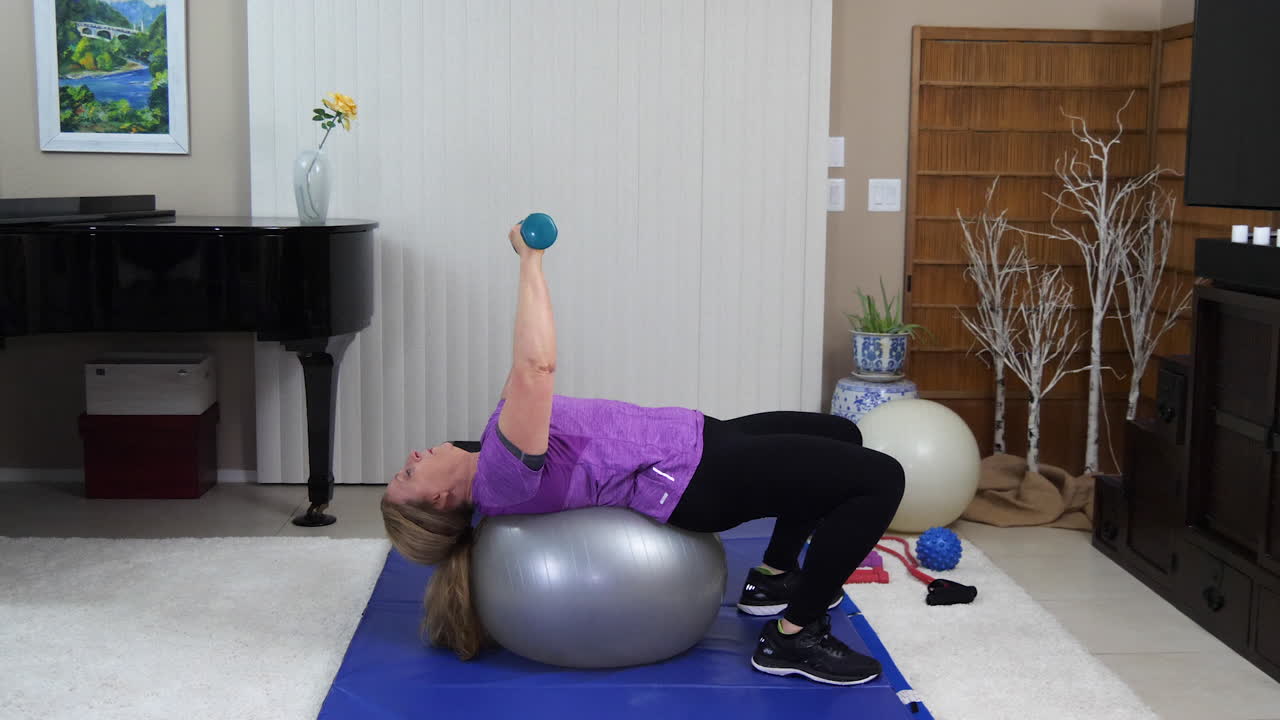 mujer realizando press de banco con pesas en la pelota de ejercicio, estática bloqueada