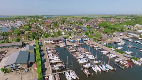 smooth orbiting shot showing marina full of sailboats and charming houses in heeg, friesland, under clear skies