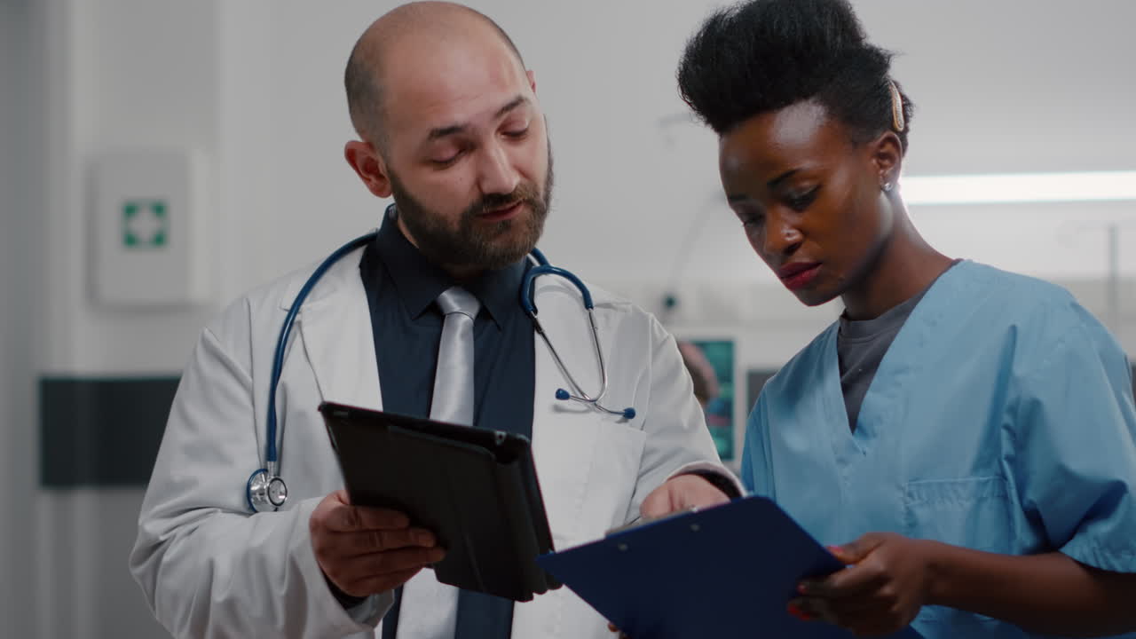 médico practicante con asistente afroamericano analizando el tratamiento de recuperación