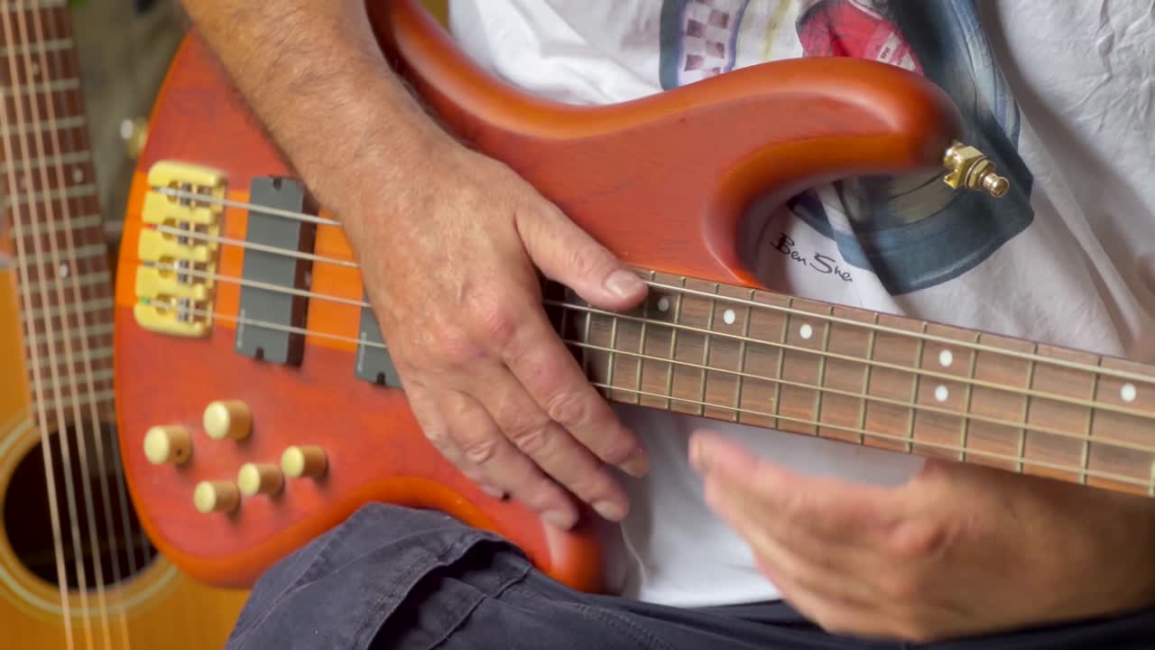 primer plano de un hombre ansioso calentándose en la guitarra bajo en un ensayo de banda