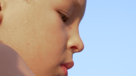 Portrait-of-boy-in-the-light-of-warm-sun-against-blue-sky