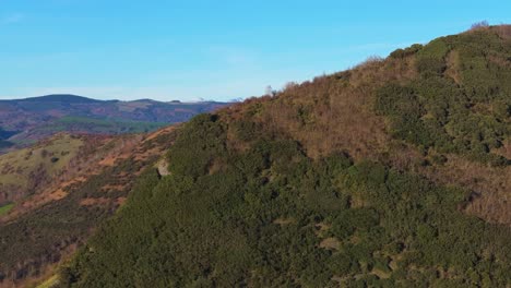 forest covered mountains with blue sky in casela, samos, spain. aerial drone shot