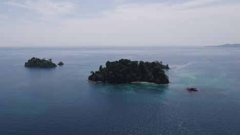 Two-lush-islands-surrounded-by-clear-blue-ocean-on-a-sunny-day,-aerial-view