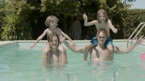 two boys sitting on father and brother's necks and having fun in the swimming pool