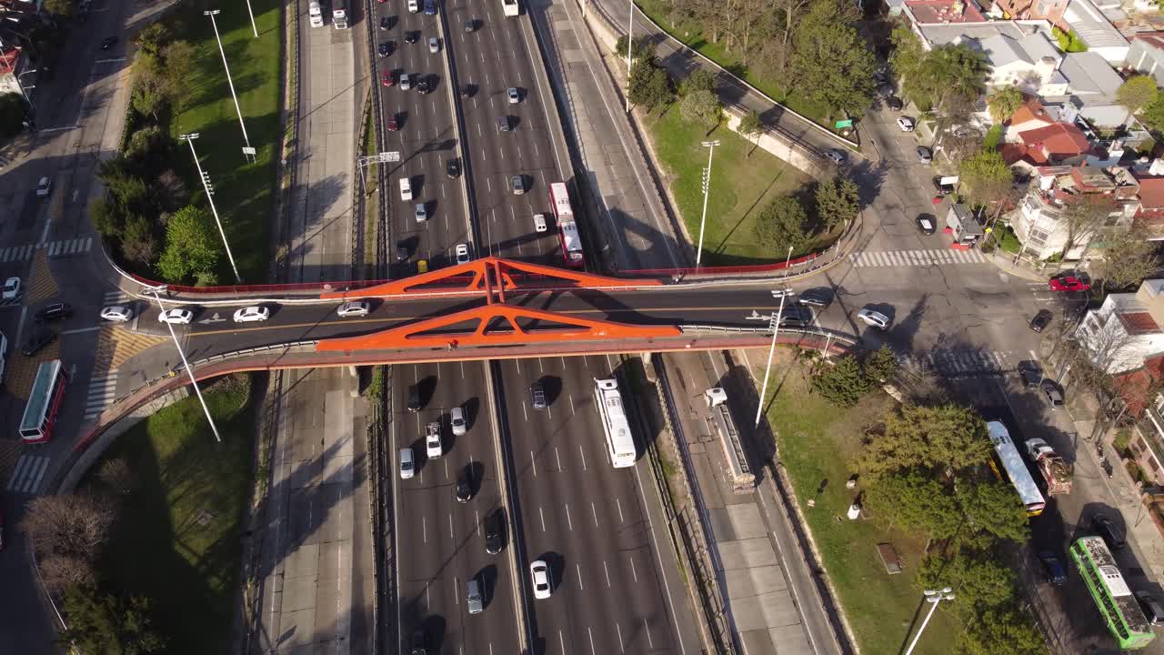 toma aérea de arriba hacia abajo de los autos que circulan por la carretera panamericana bajo el puente rojo en buenos aires