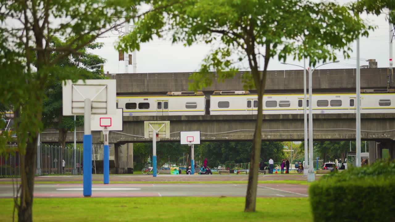parque público con canchas de baloncesto y un tren que pasa al fondo en la ciudad de taipei, taiwán