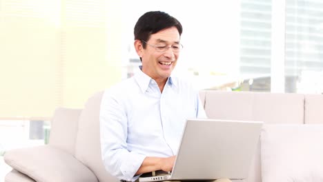 Hombre-Asiático-Usando-Una-Computadora-Portátil-En-El-Sofá