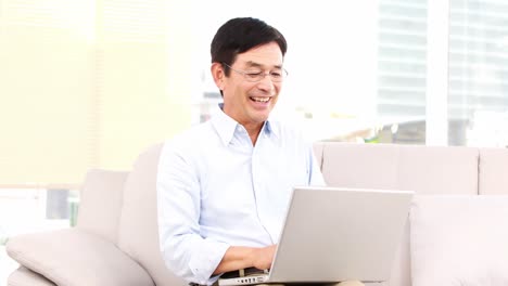 asian man using laptop on the sofa