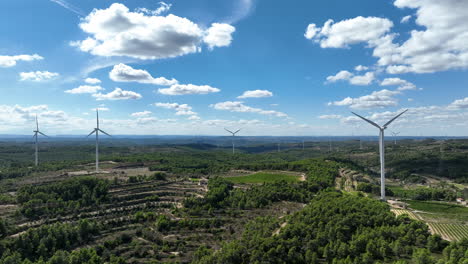 drone aerial view of wind turbines and green landscape with blue sky in catalonia, spain