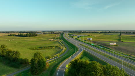 early morning aerial shot of a curving highway and exit ramps amidst green fields