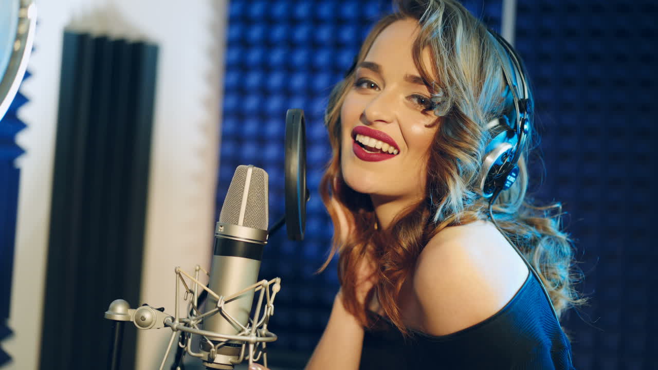 Vinnitsa, Ukraine - May 2019: The girl sings into the microphone. A young attractive woman singing in recording studio