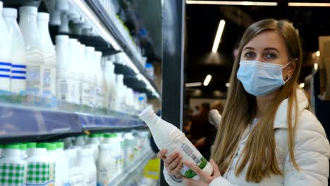 a european woman studies the composition of milk in a hypermarket. a young woman makes purchases, she buys natural milk.
