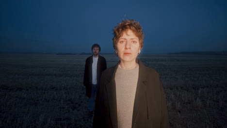 portrait of melancholic woman with boyfriend in field during blue hour