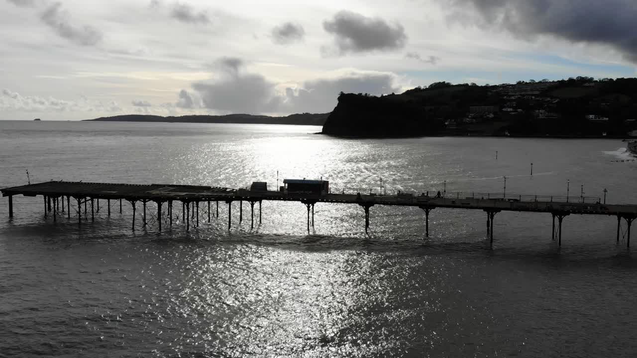 Aerial Over Silhouette Of Teignmouth's Grand Pier Reaching Out In The English Channel. Dolly Forward