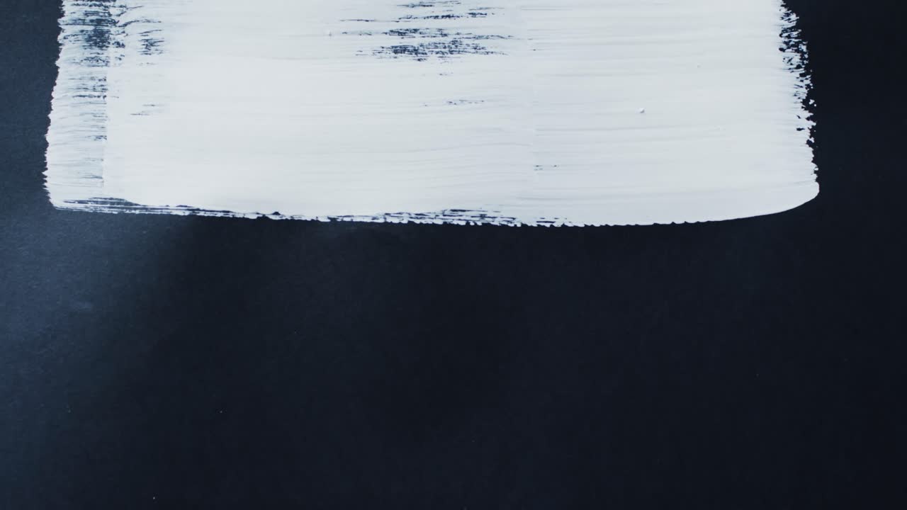primer plano de una franja de pintura blanca sobre un fondo negro con espacio de copia, cámara lenta