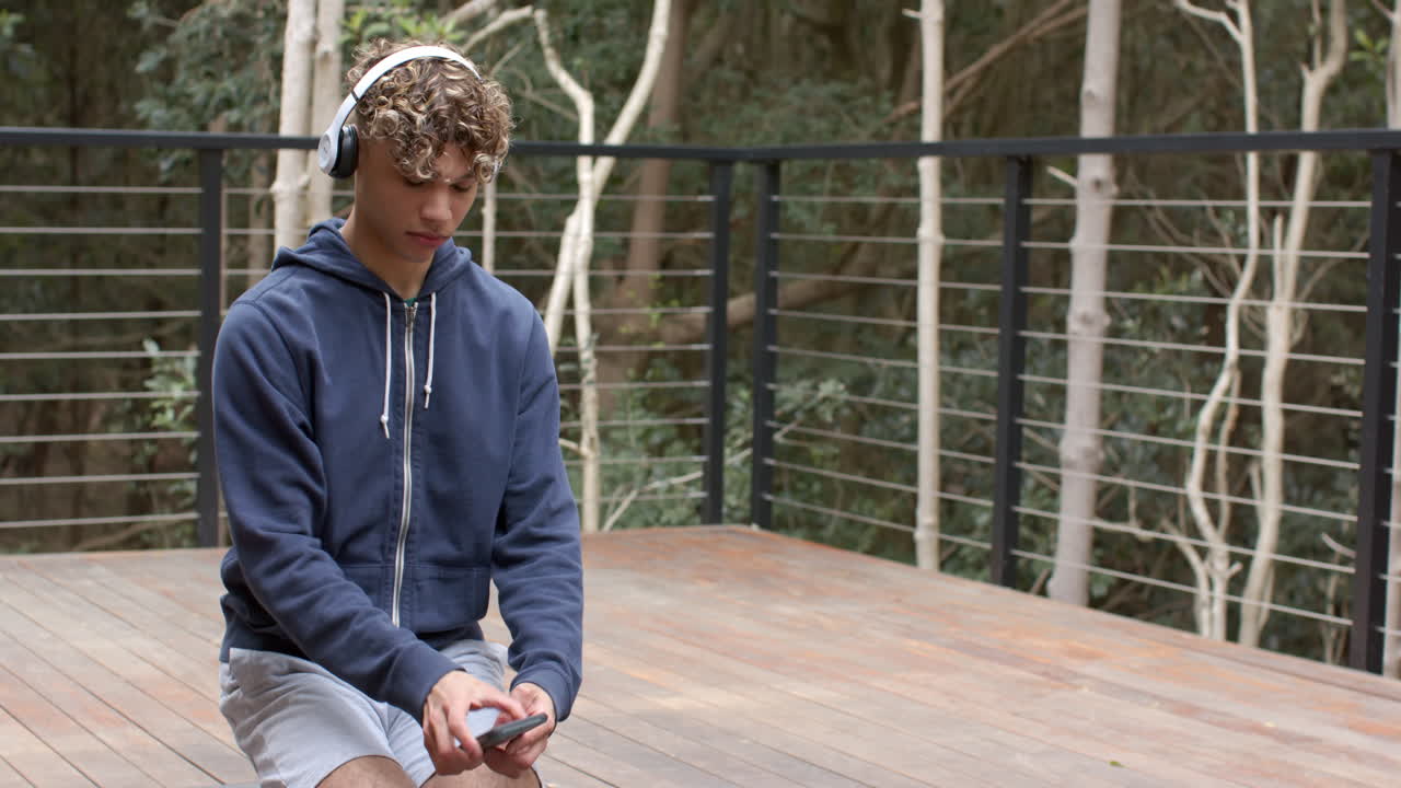 Adolescente che medita all'aperto, con le cuffie, in un ambiente forestale tranquillo.