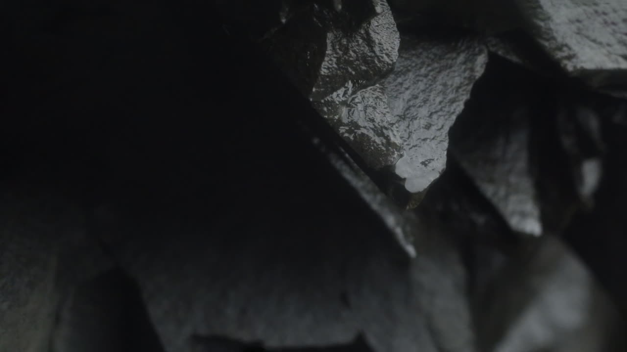 gota de agua cayendo de una pared rocosa con un patrón hexagonal único