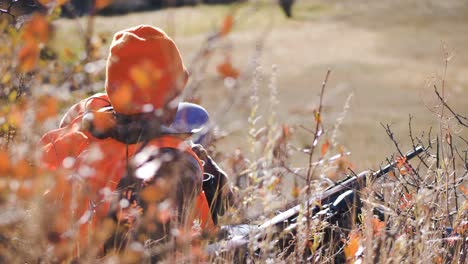 el cazador de alces mira a la distancia con binoculares mientras está acostado en el suelo