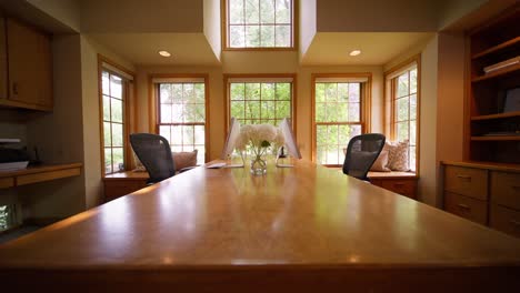 push in shot of a desk in a large home office with wood accents being lit by natural window light