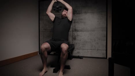 Seated-dumbbell-skull-crushers-tricep-extensions,-cinematic-lighting,-white-man-dressed-in-black-gym-attire