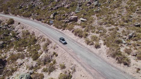 car with folded tent on the roof driving on mountain road in termas valle de colina in chile