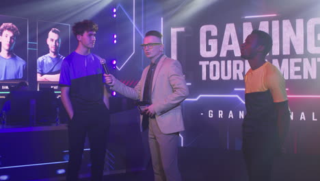 diverse gamers shaking hands after interview young man esportsman answering questions of announcer host then shaking hand of black rival and walking away at start of gaming competition