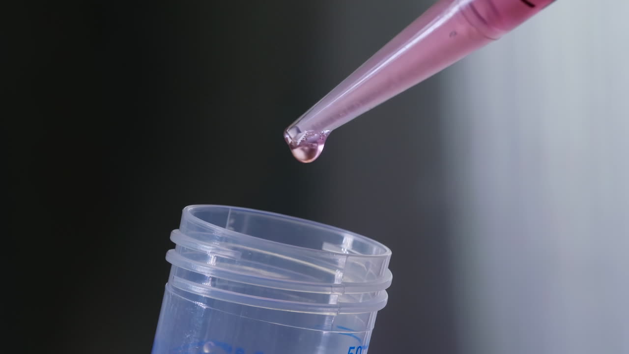 Pipette drop pink transparent liquid sample into test tube in laboratory for scientific analysis