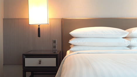 hotel room accommodation, king size bed in master suite, white sheets and pillows pan left