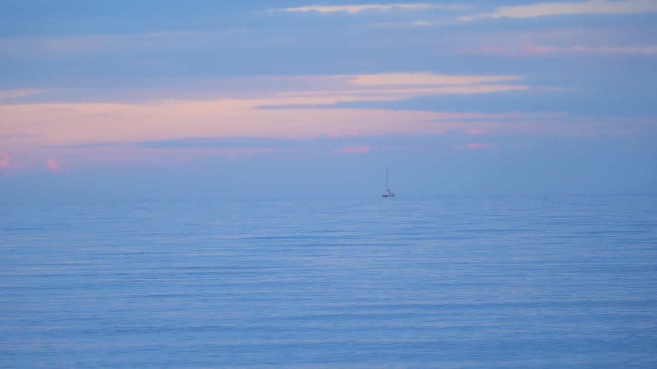저녁 황혼 시간 동안 코스타 델 솔 앞바다에 떠 있는 멀리 보이는 보트