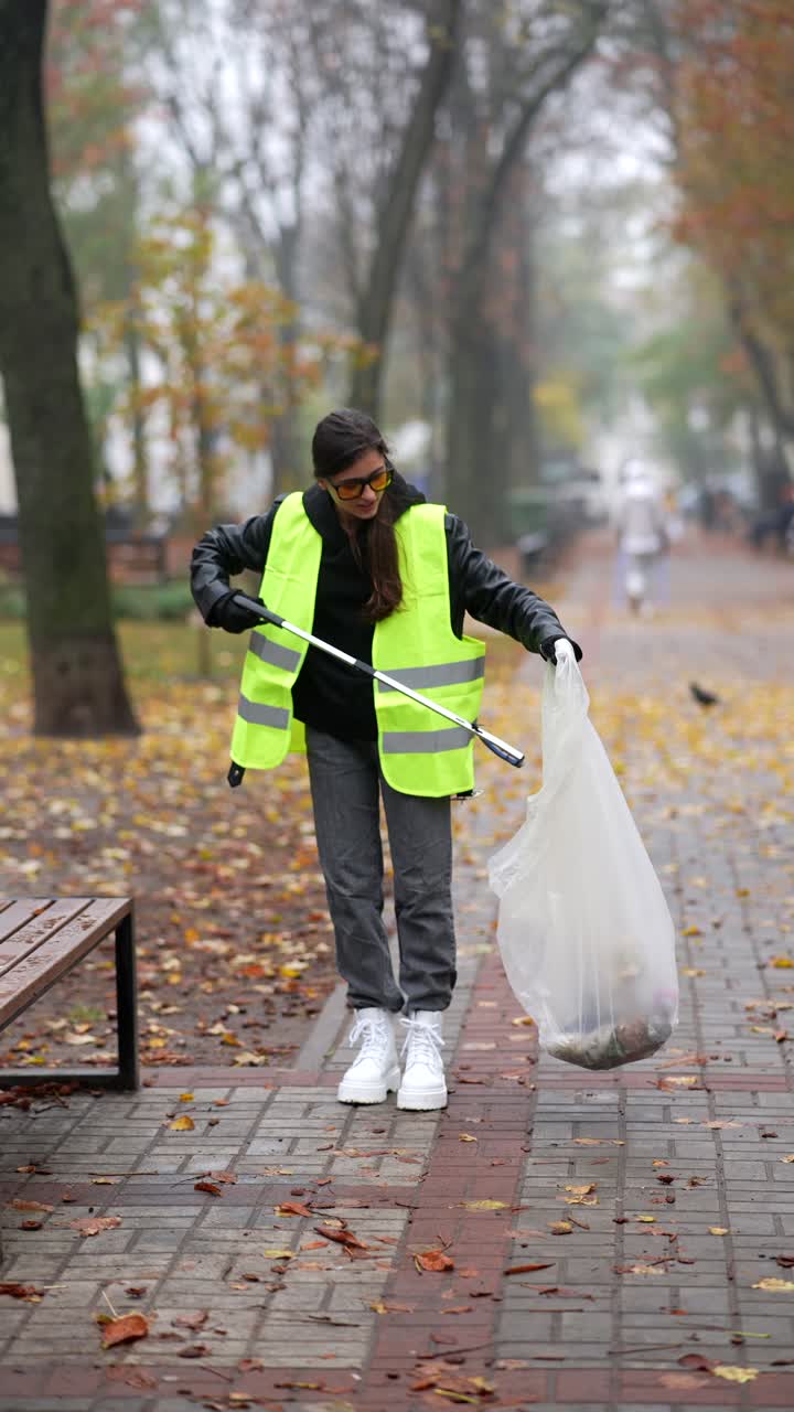 mujer limpiando un camino del parque en otoño