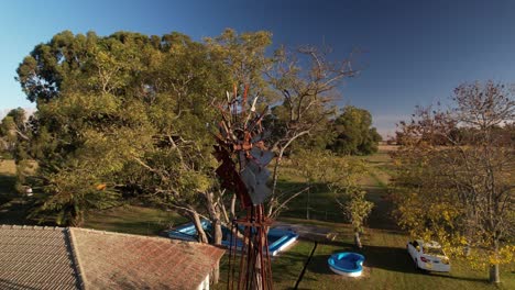 Vista-Orbital-Del-Viejo-Molino-De-Viento-Oxidado-En-Un-Terreno-De-Granja,-Argentina