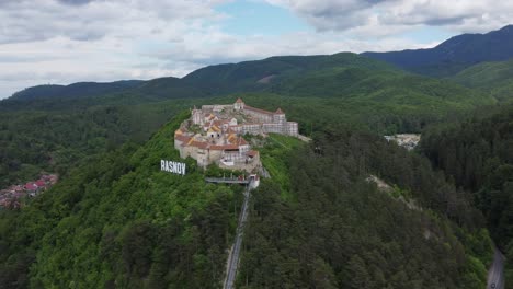 Orbiting-4K-drone-shot-of-Rasnov-hilltop-town-in-the-Carpathian-mountains,-Transylvania,-Romania