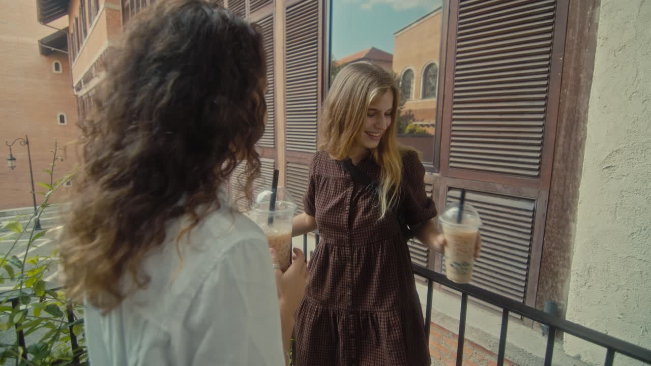 Two Friends Enjoying Bubble Tea on a Balcony