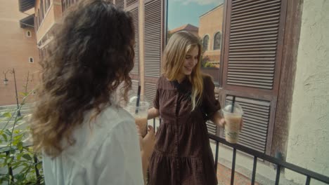 two friends enjoying bubble tea on a balcony