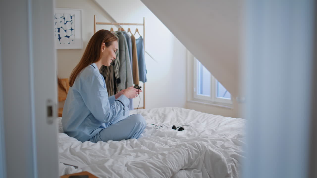 Morning girl turning music on resting bed. Excited happy woman taking headphones