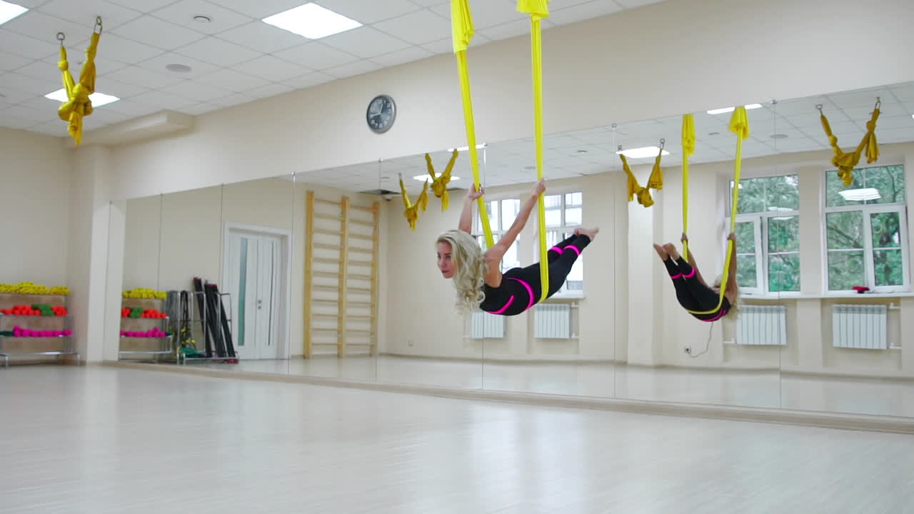 건강한 라이프 스타일을 위한 스포츠의 개념. 소녀는 백색 방에서 캔버스에서 안티그래비티 휴식을 취하고 흔들리고 있습니다.