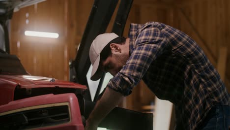 farmer repairing tractor in barn