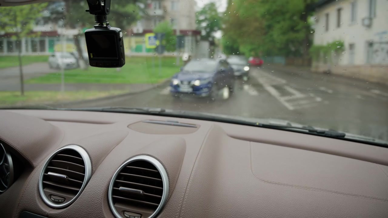 Interior view from a moving vehicle with windshield wipers clearing rainwater from the glass
