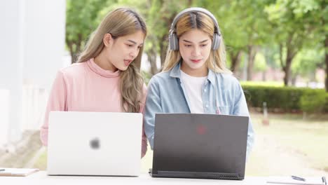 two asian girls student partners are working on a laptop help study together