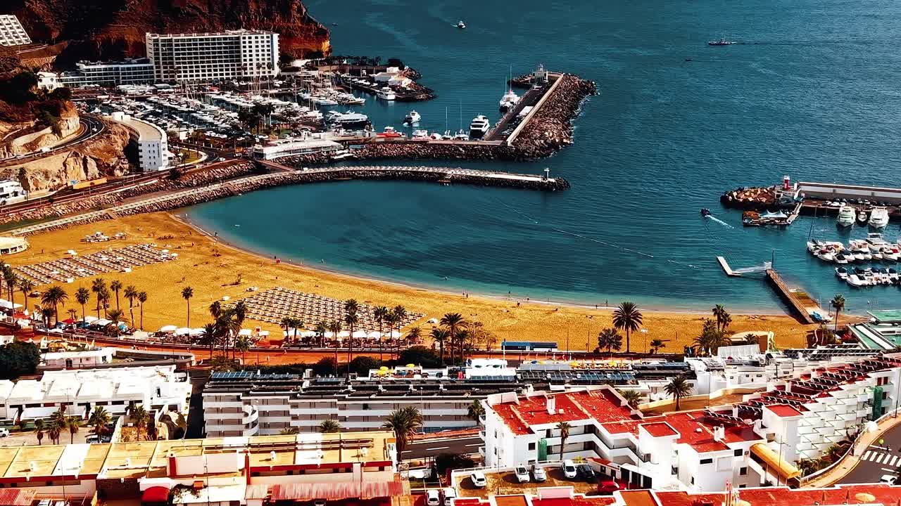 Cảnh bờ biển và bến du thuyền Gran Canaria với bãi biển và các tòa nhà.