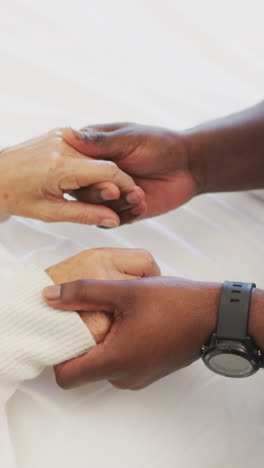 video de las manos de un médico afroamericano sosteniendo a una mujer caucásica mayor