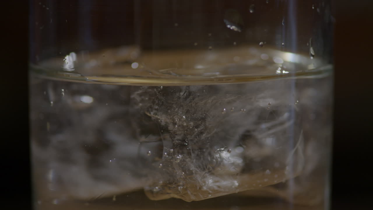 유리에 맑은 음료를 붓는 바텐더의 근접