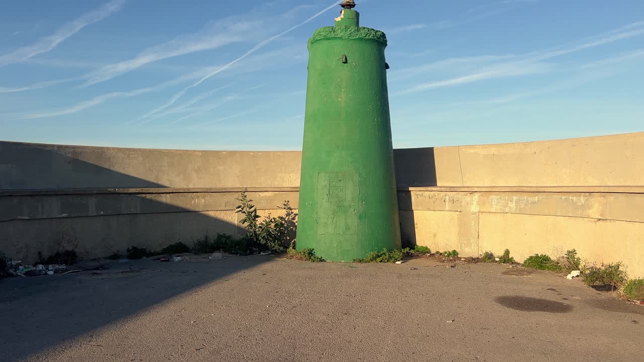 a lo largo de la costa de españa, una instalación de hormigón con silos de agua de color verde ejemplifica la mezcla armoniosa de infraestructura hecha por el hombre y ecosistemas costeros