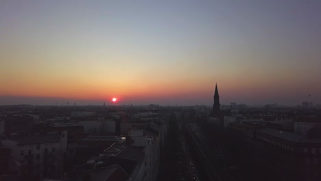 Por-Encima-De-Las-Vías-Elevadas-Del-Metro-En-Berlín-Al-Atardecer-Con-El-Paisaje-Urbano-Al-Atardecer,-La-Plataforma-Aérea-Delantera-En