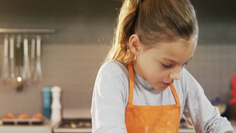 concentrated little girl wearing apron and kneading dough at kitchen 4k 4k