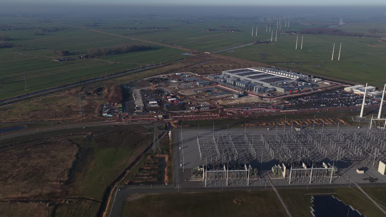 Filmagem aérea com drone de um enorme data center de hiperescala em construção em Westpoort, Groningen, destacando o consumo extremo de eletricidade, a infraestrutura da rede elétrica e a computação em nuvem em larga escala