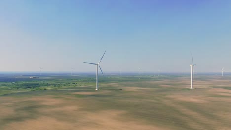 wide drone pov, empty, lands, couple of wind turbines, wind power station, farmland, drone, flying, wind farm, sunny day, blue sky, hazy morning, aerial view, texas san roman wind park, aerial shot