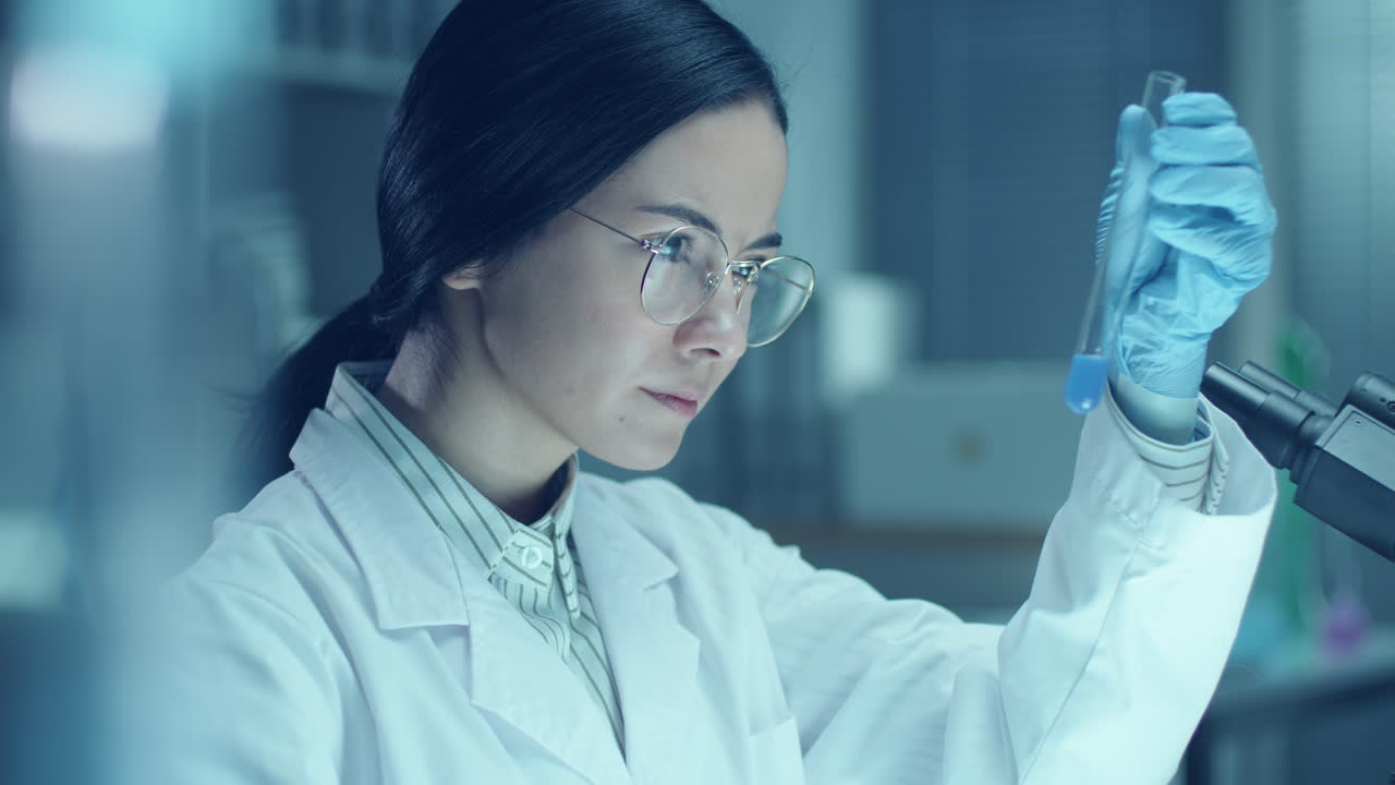 Female Scientist Examining Test Tube with Blue Liquid in Laboratory