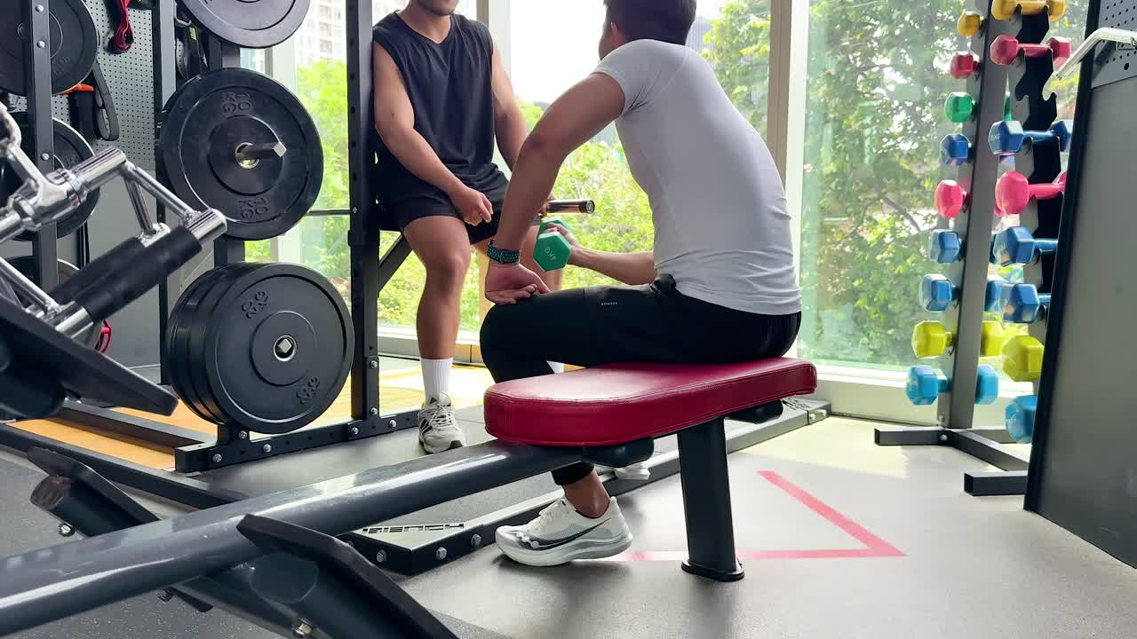 A trainer guides a client through exercises in a well-equipped gym with natural lighting and motivational atmosphere